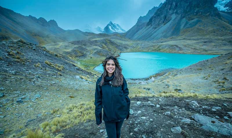 Traveler at a turquoise mountain lake during the Ausangate 7 Lagunas trek in Peru