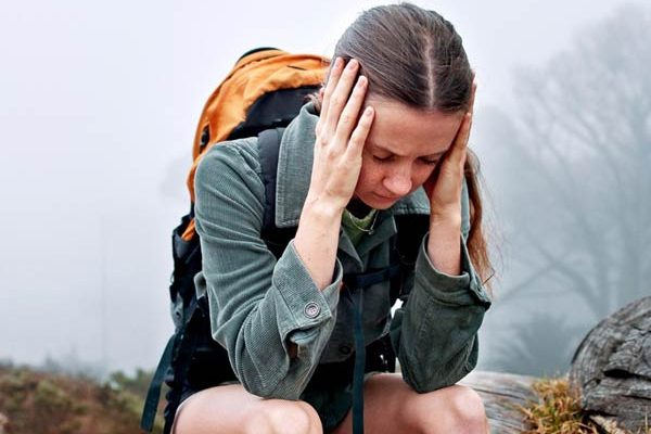 Hiker experiencing headache during high-altitude trek in the Andes mountains with scenic mountain trail in the background