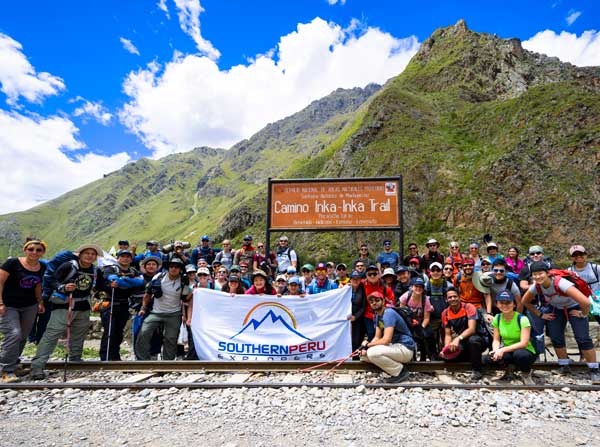 A group of travelers walks along the Inca Trail, while behind them the ancient Inca path stretches through the Andes, surrounded by breathtaking landscapes on the way to Machu Picchu, Tour Operators