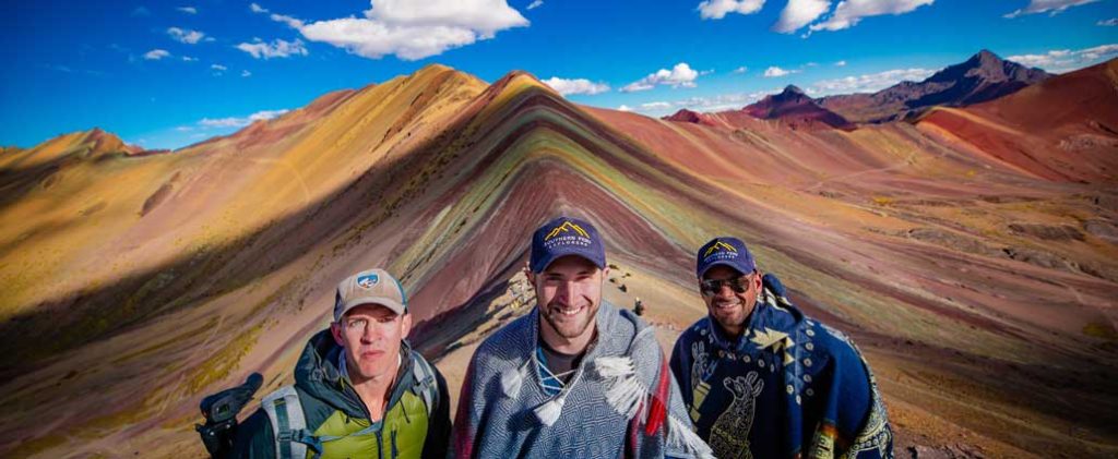 Rainbow Mountain in Peru displaying its vibrant multicolored mineral slopes, surrounded by dramatic Andean peaks and high-altitude landscapes.