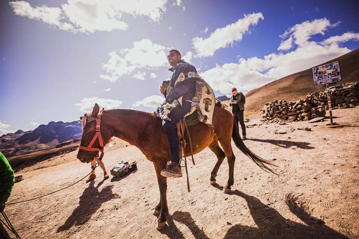Tourist riding a horse at the starting point of the Rainbow Mountain trek, surrounded by scenic Andean landscapes and high-altitude valleys. Rainbow Mountain F.A.Q
