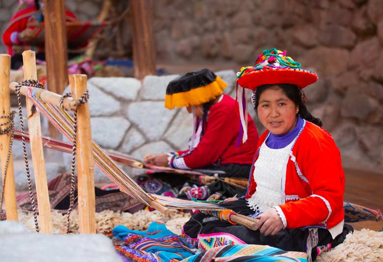 Woman doing traditional weaving in Peru using a hand loom with colorful Andean textiles and alpaca wool in a rural highland setting