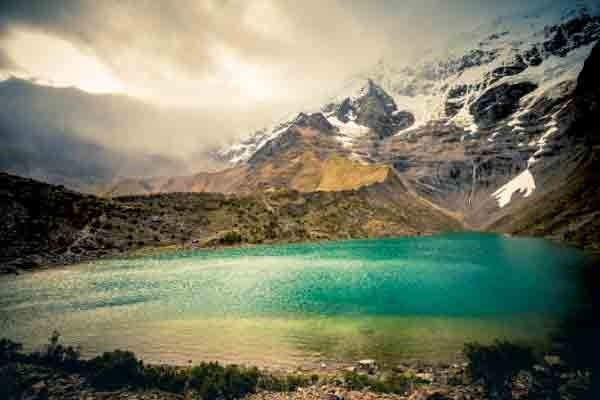 2026, A stunning turquoise Humantay Lake surrounded by snow-capped mountains and rugged Andean peaks in Peru.
