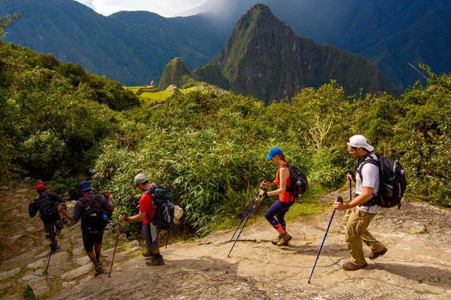 Hikers walking along the Inca Trail to Machu Picchu with ancient stone pathways, mountain scenery, and archaeological sites in Peru, Peru Tour